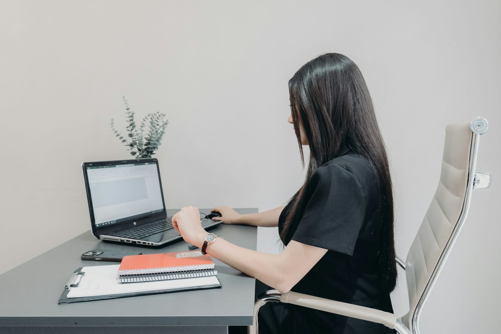 Frau arbeitet an einem hellen Schreibtisch am Laptop